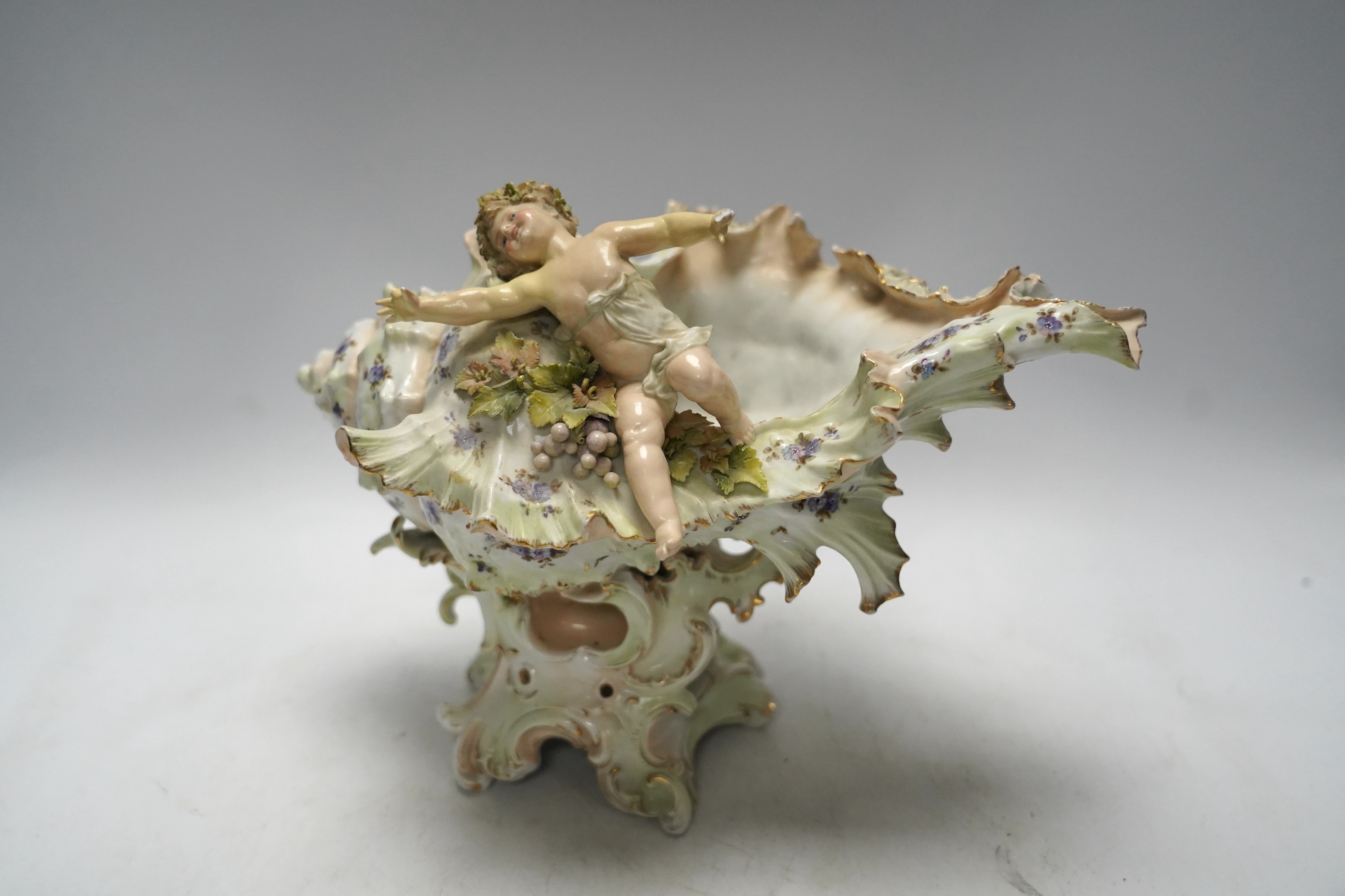 A porcelain shell-shaped centrepiece, a Dresden pill box, a pair of taper holders and a porcelain figure, tallest 21cm